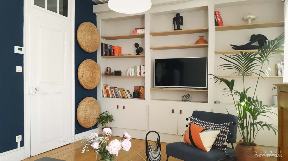 Esempio di un grande soggiorno eclettico con libreria, pareti blu, parquet chiaro e TV autoportante