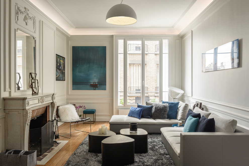 Mittelgroßes, Fernseherloses, Abgetrenntes Klassisches Wohnzimmer mit weißer Wandfarbe, braunem Holzboden, Kamin, braunem Boden und Kaminumrandung aus Stein in Paris