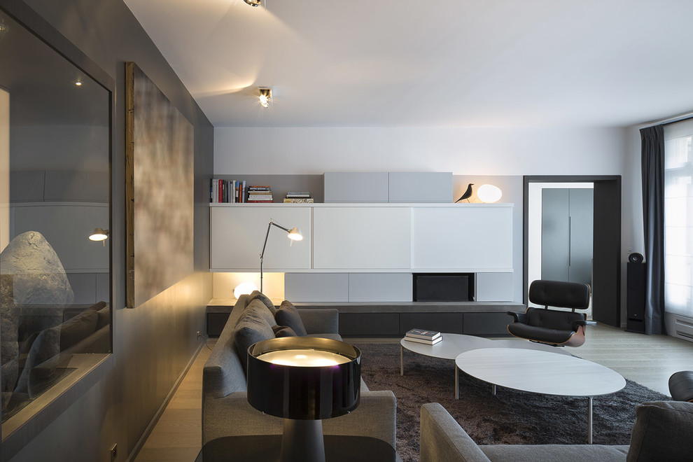 Cette image montre un grand salon design ouvert avec une salle de réception, un mur multicolore, parquet clair et un téléviseur dissimulé.