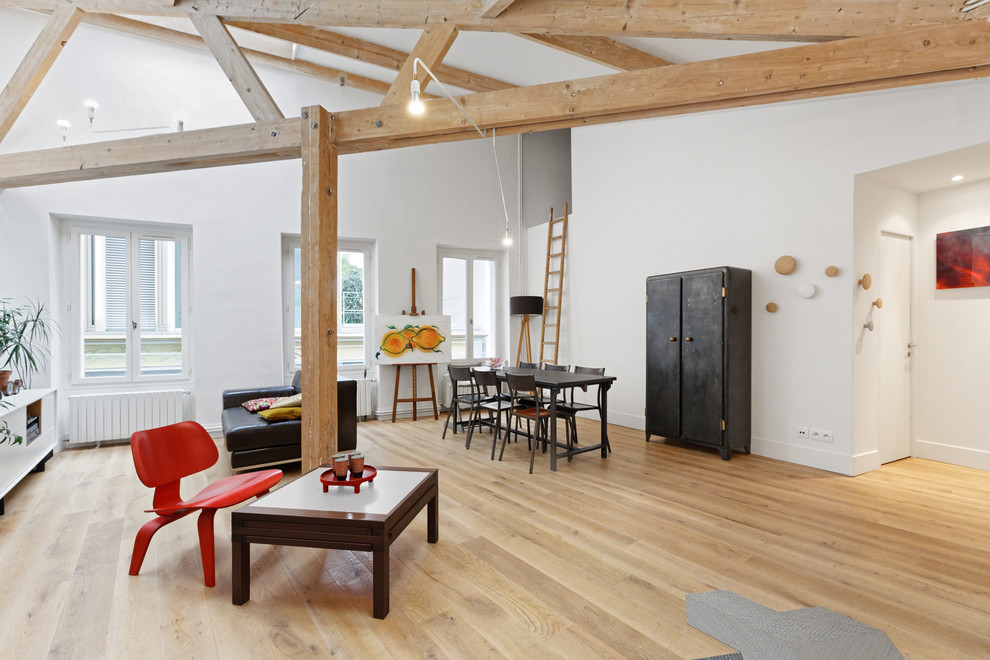 Réalisation d'un salon design de taille moyenne et ouvert avec un mur blanc, un sol en bois brun et canapé noir.