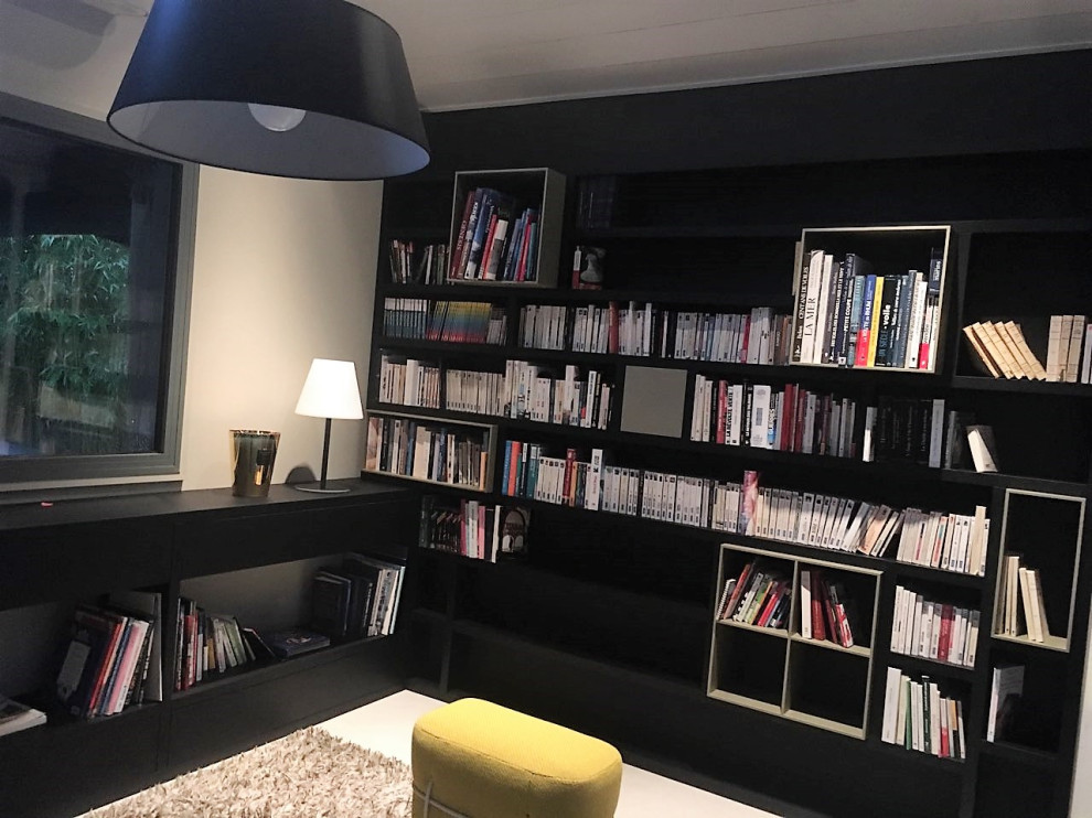 Ejemplo de biblioteca en casa abierta actual grande sin chimenea y televisor con paredes beige, suelo de cemento y suelo beige