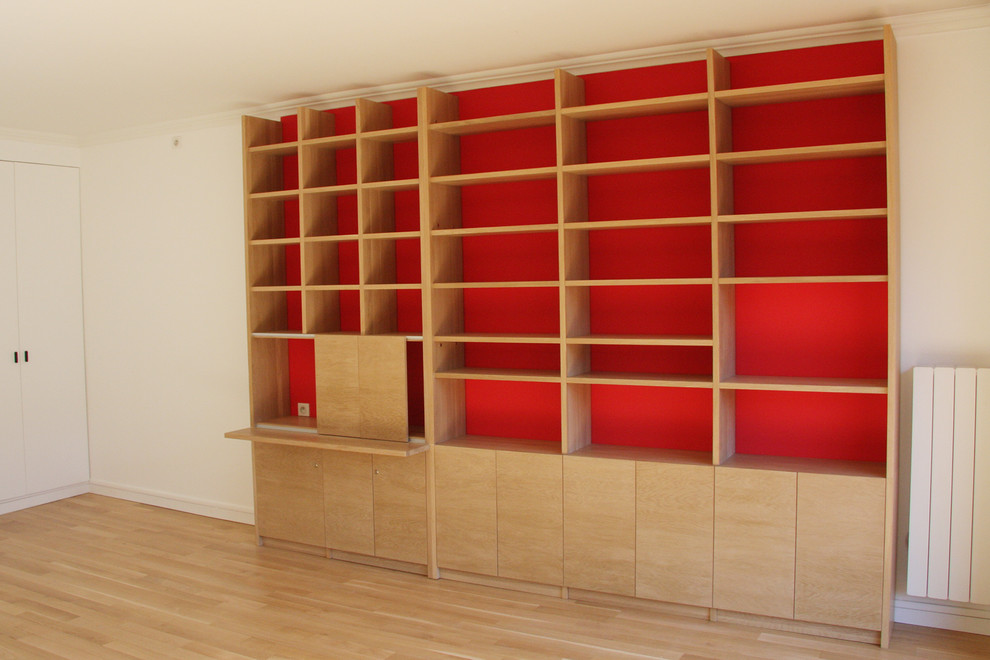 Стильный дизайн: большая открытая гостиная комната в стиле модернизм с с книжными шкафами и полками, красными стенами, светлым паркетным полом и отдельно стоящим телевизором - последний тренд