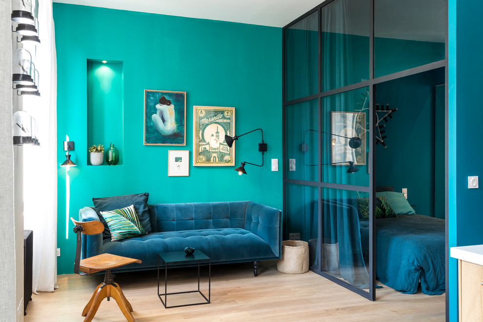 Cette image montre un salon bohème ouvert avec un mur bleu, parquet clair et aucune cheminée.