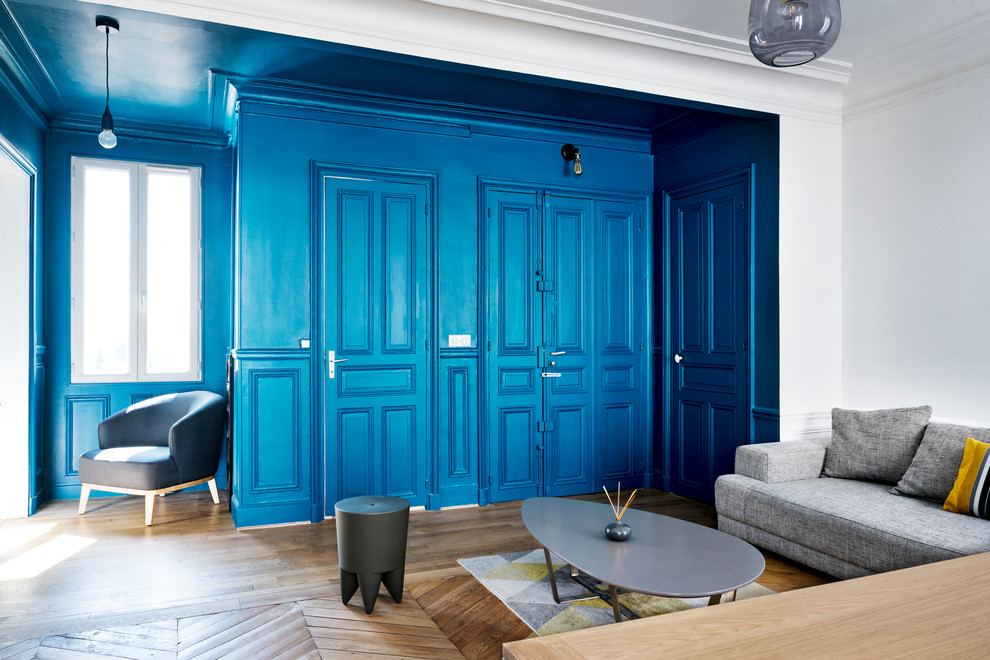 Idées déco pour un salon rétro de taille moyenne et ouvert avec une salle de réception, un mur bleu, parquet clair, un téléviseur indépendant et un sol marron.