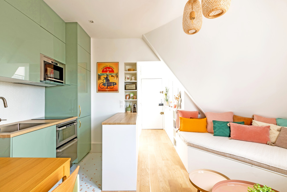 Пример оригинального дизайна: открытая гостиная комната среднего размера в стиле шебби-шик с с книжными шкафами и полками, белыми стенами, светлым паркетным полом, телевизором на стене и коричневым полом без камина