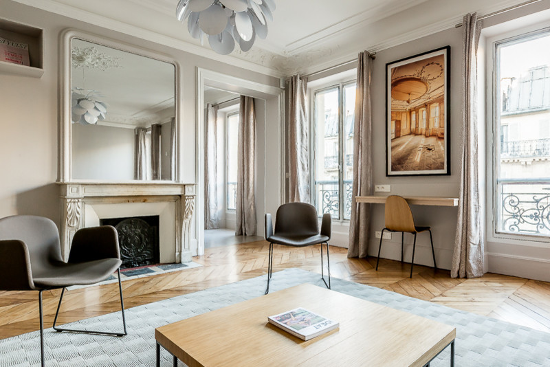 Klassisches Wohnzimmer mit weißer Wandfarbe, dunklem Holzboden, Kamin und beigem Boden in Paris