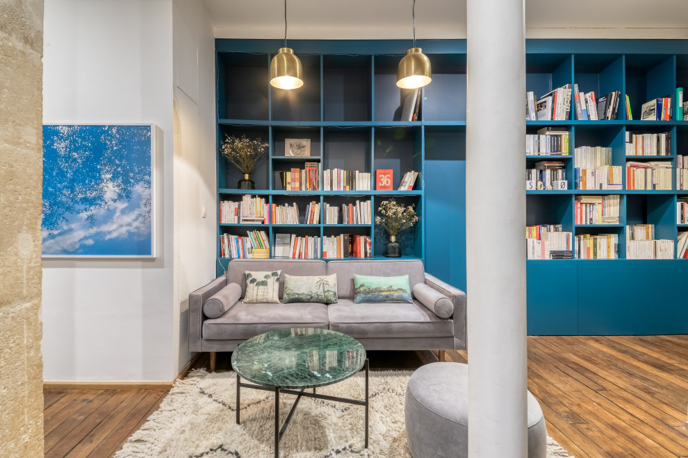 Exemple d'un bureau tendance de taille moyenne avec une bibliothèque ou un coin lecture, un mur bleu, un sol en bois brun, aucune cheminée, un sol marron et un bureau indépendant.