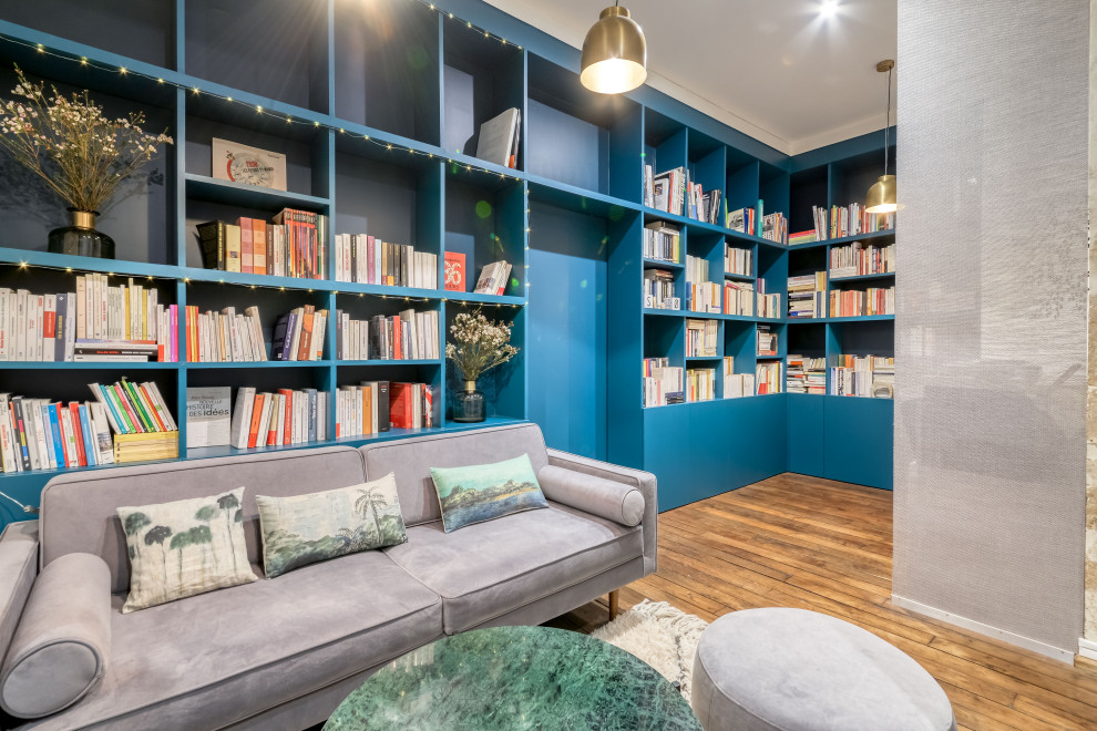 Immagine di uno studio contemporaneo di medie dimensioni con libreria, pareti blu, pavimento in legno massello medio, nessun camino, pavimento marrone e scrivania autoportante