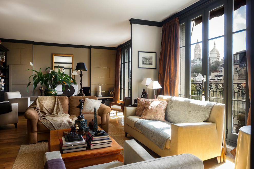 Klassisches Wohnzimmer mit beiger Wandfarbe, hellem Holzboden, Kamin und Kaminumrandung aus Stein in Paris