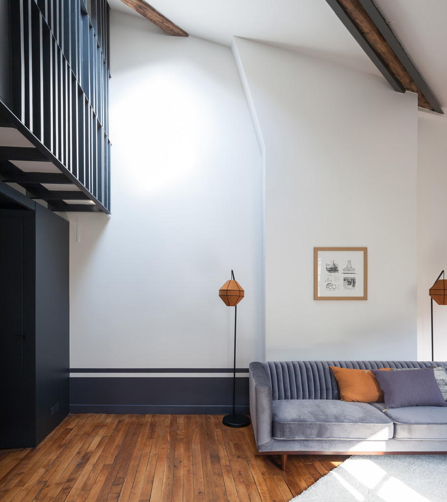Mid-sized danish loft-style medium tone wood floor living room photo in Paris with blue walls, no fireplace and no tv