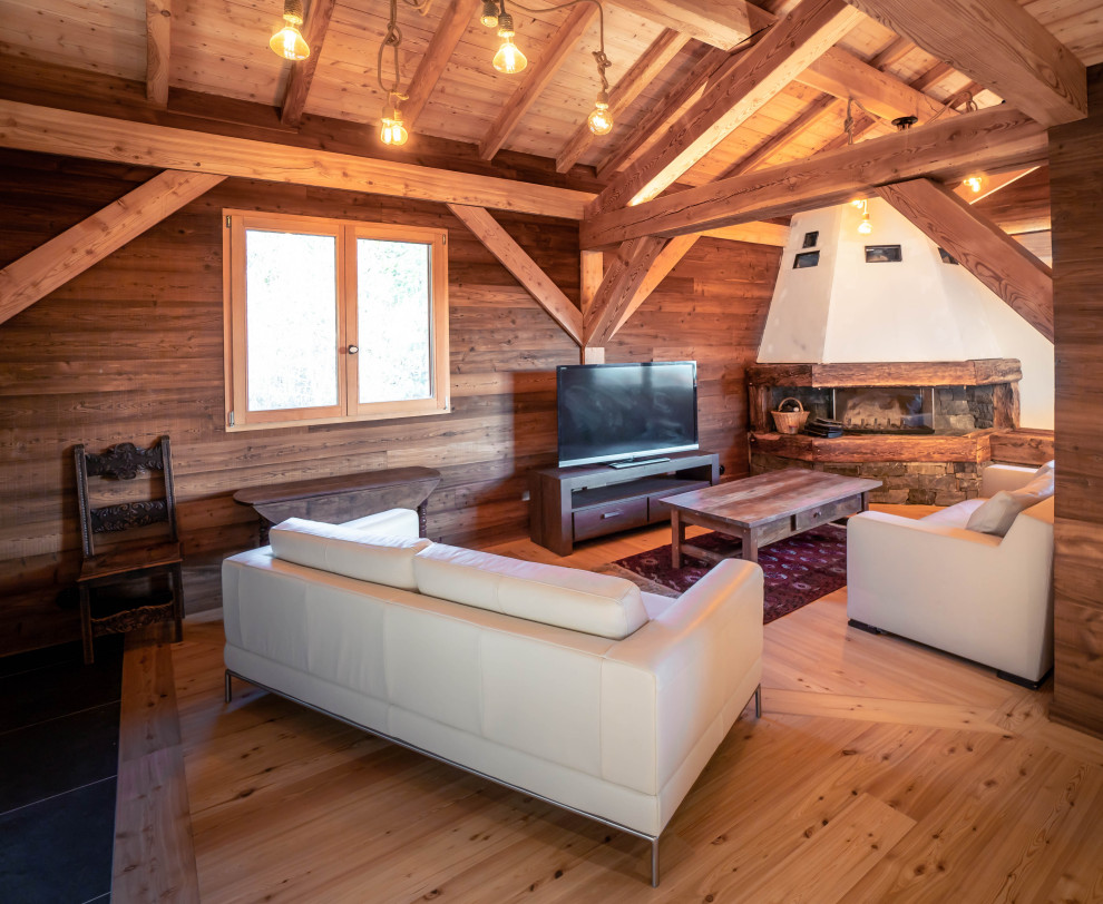 Réalisation d'un salon chalet en bois ouvert avec un sol en bois brun, une cheminée d'angle et un plafond en bois.