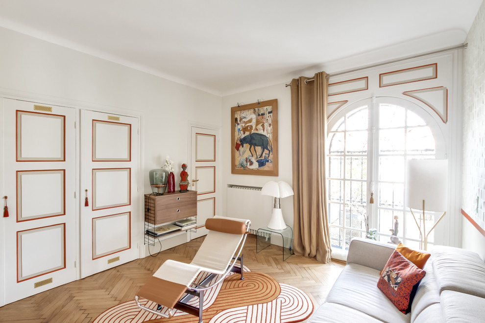 Cette image montre un salon traditionnel de taille moyenne et fermé avec un mur beige, parquet clair, une bibliothèque ou un coin lecture, un téléviseur fixé au mur et un sol beige.