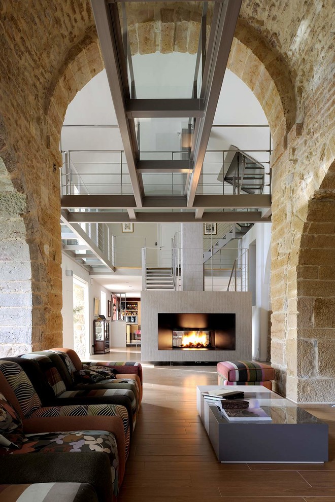 Offenes, Großes, Fernseherloses Industrial Wohnzimmer mit Tunnelkamin, beiger Wandfarbe, Keramikboden und Steinwänden in Lyon