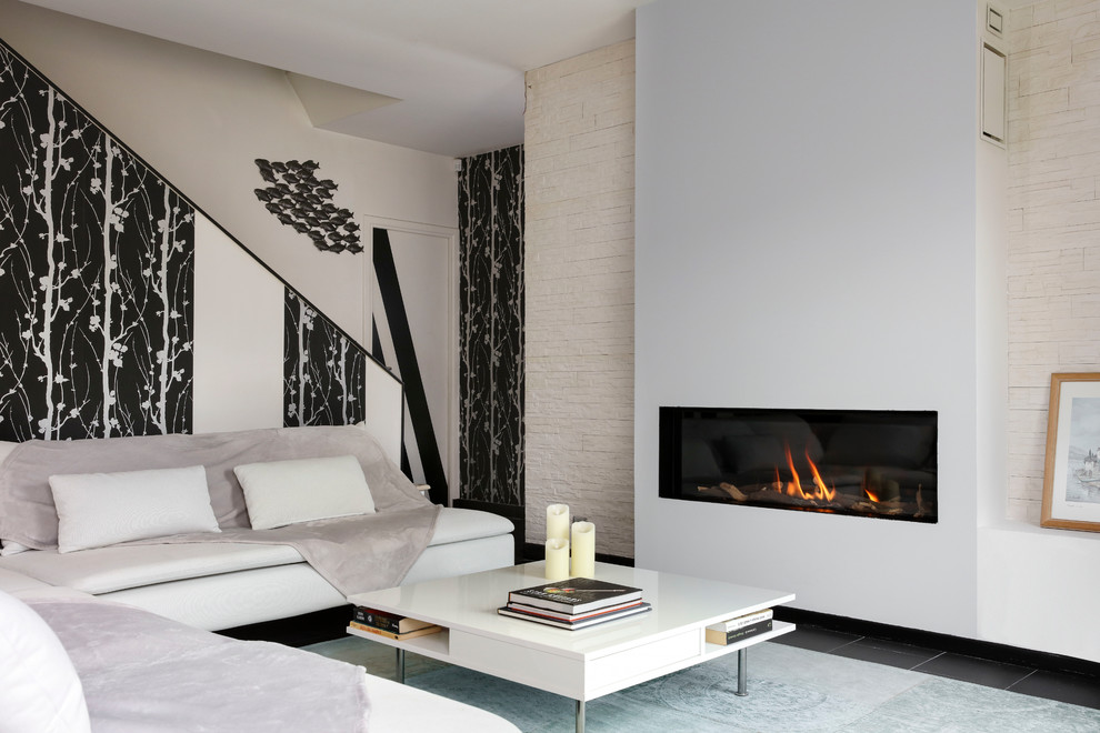 Idée de décoration pour un grand salon design avec un mur beige, une cheminée standard, aucun téléviseur, un sol noir et un escalier.