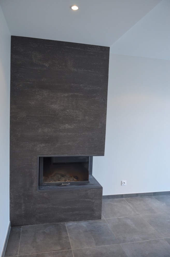 Стильный дизайн: открытая гостиная комната среднего размера в стиле лофт с серыми стенами, полом из керамической плитки, угловым камином и фасадом камина из штукатурки без телевизора - последний тренд
