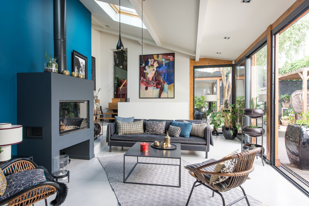 Exempel på ett eklektiskt vardagsrum, med blå väggar, betonggolv, en standard öppen spis och grått golv
