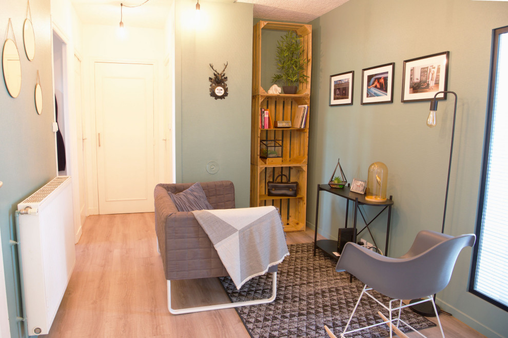 This is an example of an urban enclosed living room in Lyon with a reading nook, green walls, beige floors and laminate floors.