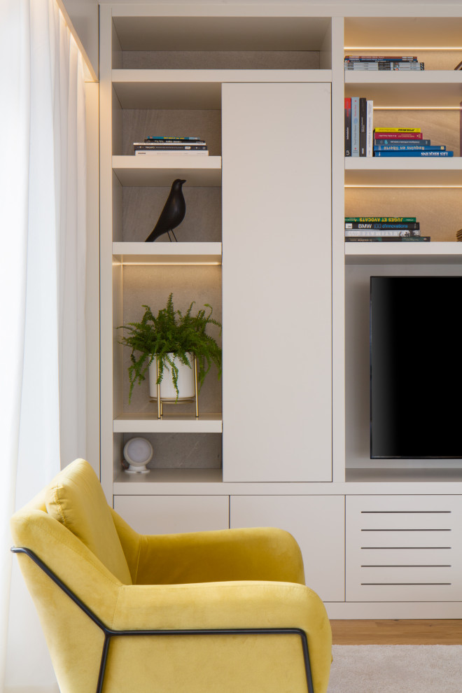 Diseño de biblioteca en casa abierta contemporánea grande sin chimenea con paredes blancas, suelo de madera clara, televisor colgado en la pared y suelo marrón