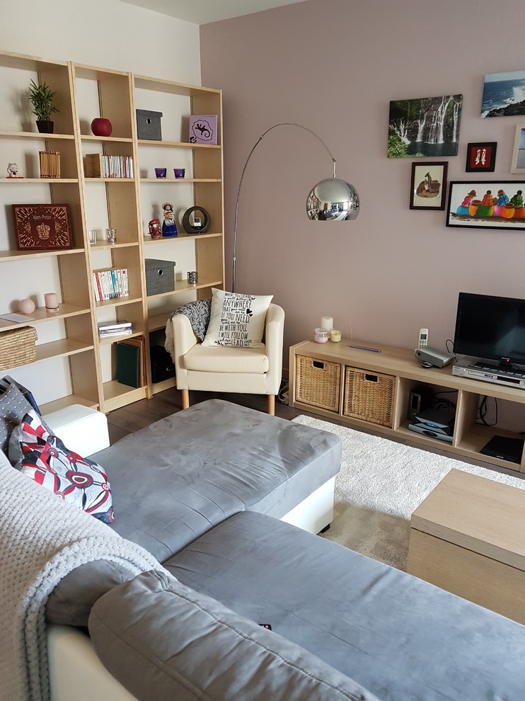 Photo of a medium sized scandinavian open plan living room in Lyon with pink walls, laminate floors, a freestanding tv and grey floors.