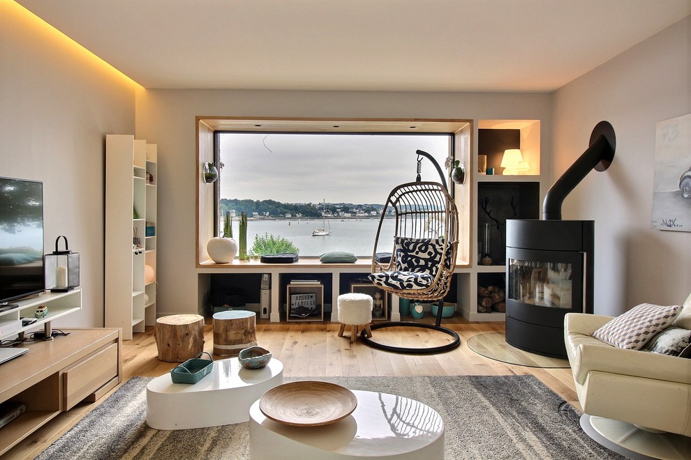 Esempio di un soggiorno minimal con pareti grigie, pavimento in legno massello medio, stufa a legna, TV autoportante e pavimento marrone