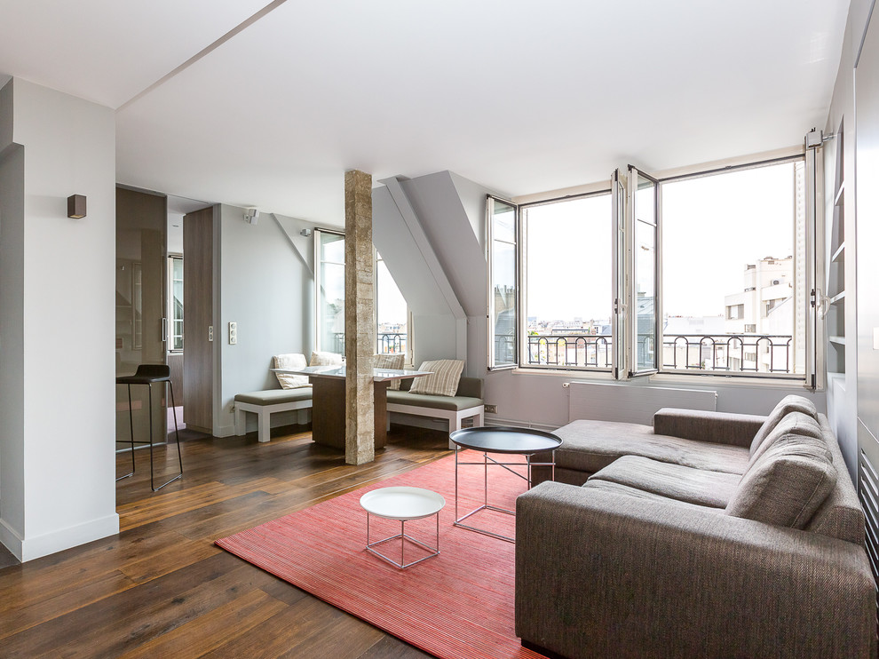 Offenes, Großes, Fernseherloses Modernes Wohnzimmer ohne Kamin mit grauer Wandfarbe und braunem Holzboden in Paris