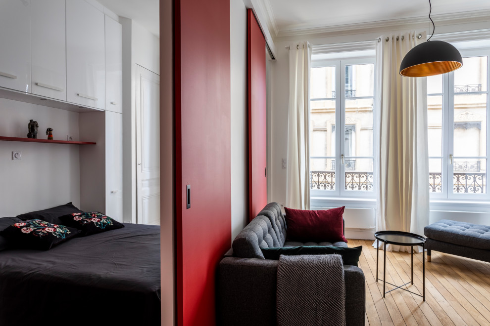 Immagine di un piccolo soggiorno minimalista aperto con pareti rosse, parquet chiaro, camino classico, cornice del camino in legno, TV nascosta, pavimento beige, soffitto ribassato e boiserie