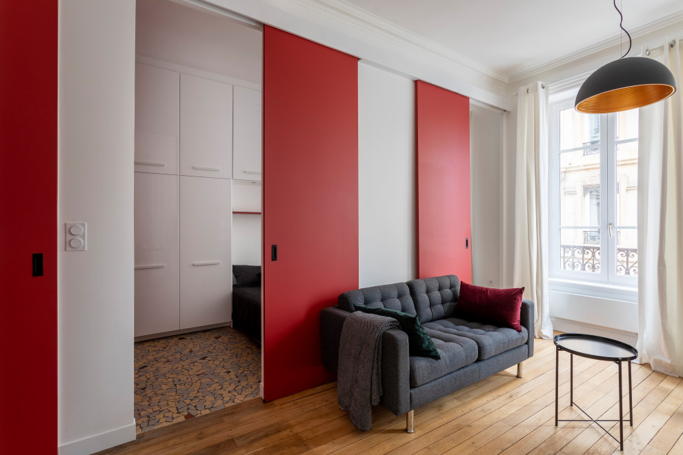 Exemple d'un petit salon moderne ouvert avec un mur rouge, parquet clair, une cheminée standard, un manteau de cheminée en bois, un téléviseur dissimulé, un sol beige, un plafond décaissé et boiseries.