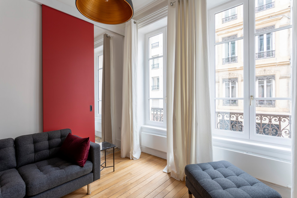 Exemple d'un petit salon moderne ouvert avec un mur rouge, parquet clair, une cheminée standard, un manteau de cheminée en bois, un téléviseur dissimulé, un sol beige, un plafond décaissé et boiseries.