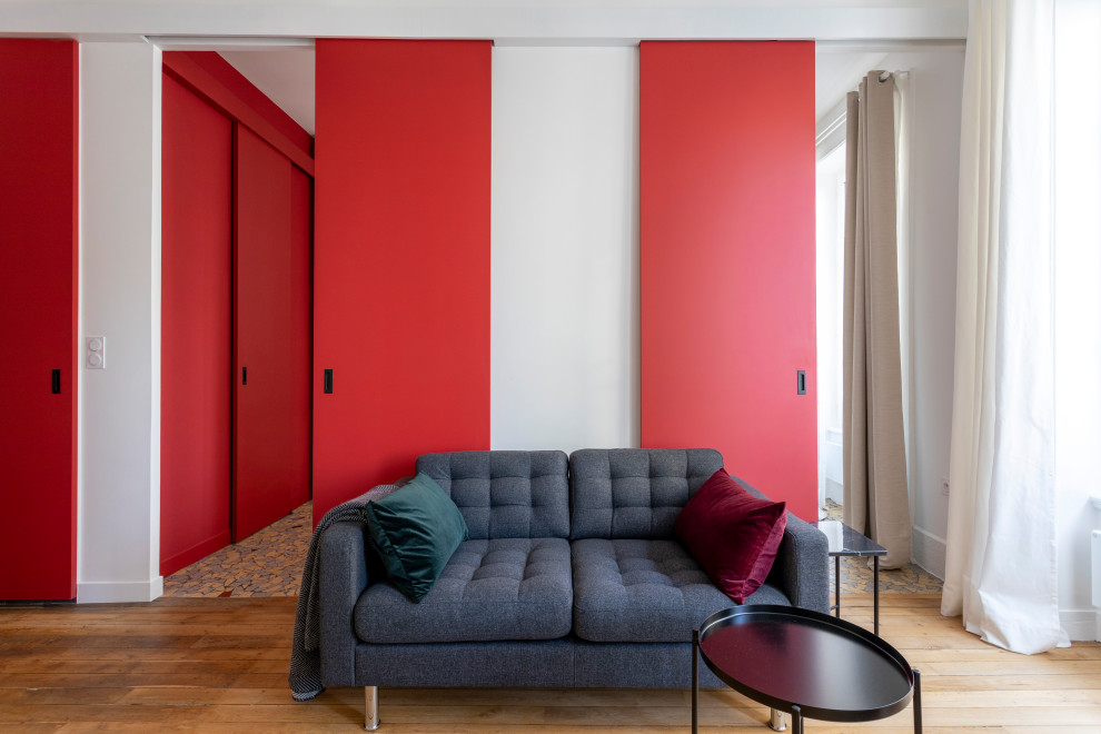 Aménagement d'un petit salon contemporain ouvert avec un mur rouge, parquet clair, une cheminée standard, un manteau de cheminée en bois, un téléviseur dissimulé, un sol beige, un plafond décaissé et boiseries.