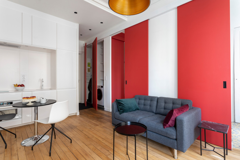 Idées déco pour un petit salon moderne ouvert avec un mur rouge, parquet clair, une cheminée standard, un manteau de cheminée en bois, un téléviseur dissimulé, un sol beige, un plafond décaissé et boiseries.