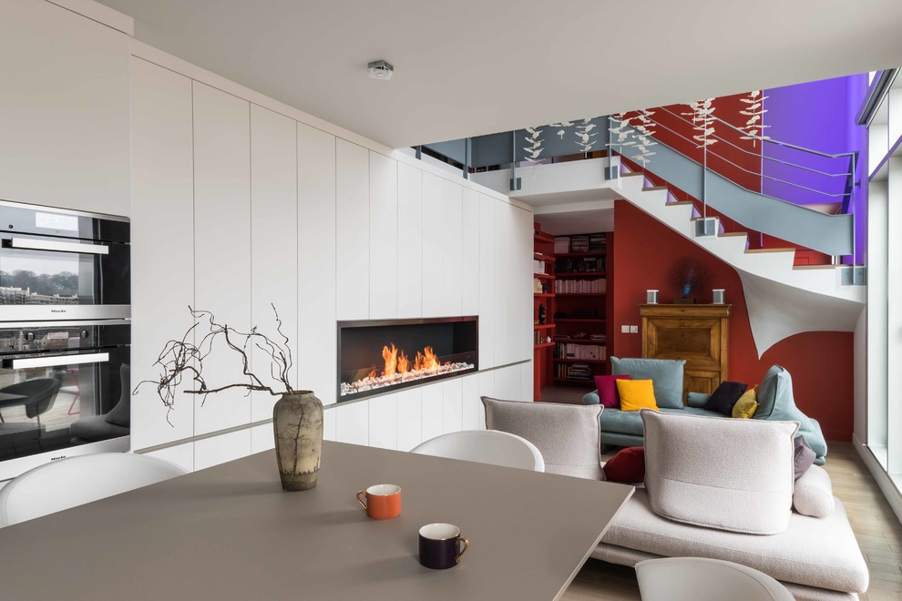 Cette image montre un grand salon design ouvert avec une salle de réception, un mur blanc, parquet clair, une cheminée standard, un manteau de cheminée en bois et un téléviseur dissimulé.