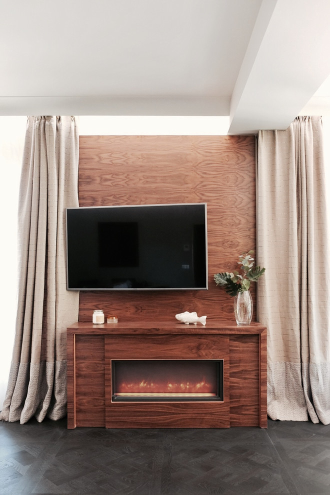 Exemple d'un grand salon chic ouvert avec un manteau de cheminée en bois, un téléviseur fixé au mur, un sol noir et un mur marron.