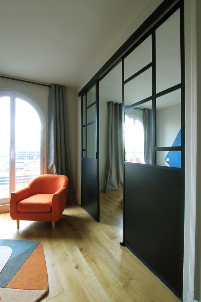 Immagine di un piccolo soggiorno contemporaneo chiuso con libreria, pareti blu, parquet chiaro e TV nascosta