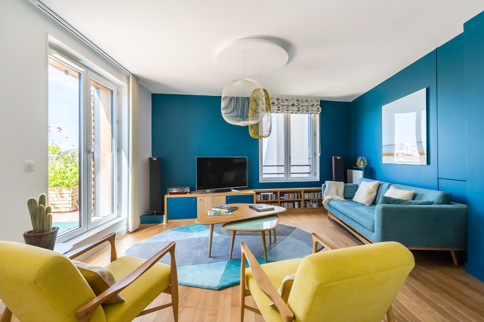 Esempio di un soggiorno minimalista con pareti blu, pavimento in legno massello medio, TV autoportante e pavimento marrone