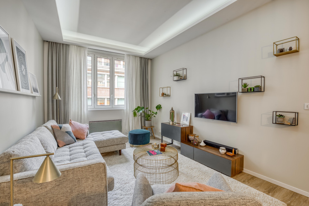 Modelo de salón abierto romántico de tamaño medio sin chimenea con paredes beige, suelo de madera clara, televisor colgado en la pared y suelo beige