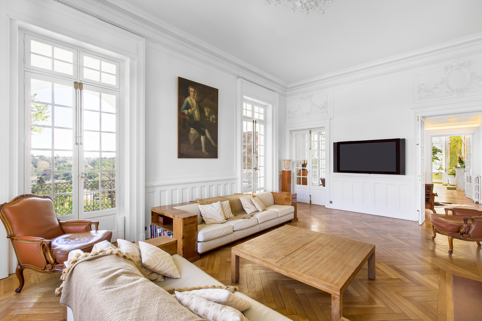 Aménagement d'un salon classique avec un mur blanc, un sol en bois brun, un téléviseur fixé au mur et un sol marron.