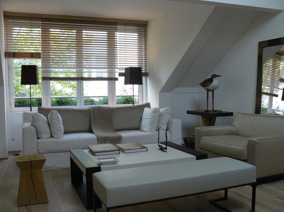 На фото: изолированная гостиная комната среднего размера в современном стиле с белыми стенами, полом из фанеры, отдельно стоящим телевизором и коричневым полом без камина