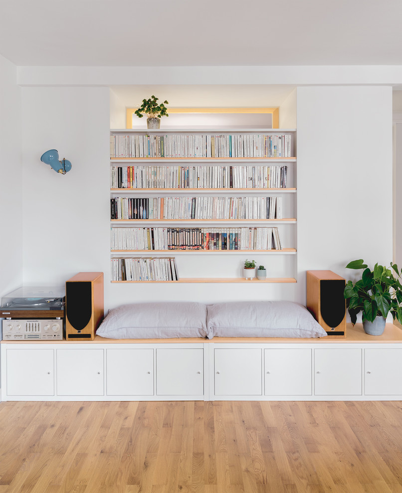 Inspiration för ett mellanstort nordiskt vardagsrum, med ett bibliotek, vita väggar, ljust trägolv och en fristående TV