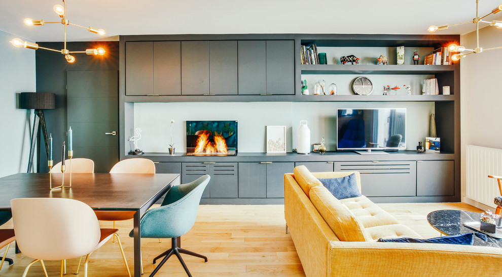 Cette image montre un salon design de taille moyenne et ouvert avec un mur bleu, parquet clair, une cheminée standard, un manteau de cheminée en métal, un téléviseur indépendant, un sol beige et éclairage.