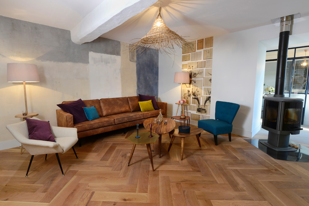 Immagine di un grande soggiorno minimalista aperto con pareti grigie, parquet chiaro, stufa a legna, sala formale e nessuna TV
