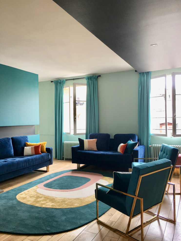 Exemple d'un salon tendance de taille moyenne et ouvert avec une salle de réception, un mur bleu, parquet clair, une cheminée d'angle, un manteau de cheminée en plâtre et un sol beige.