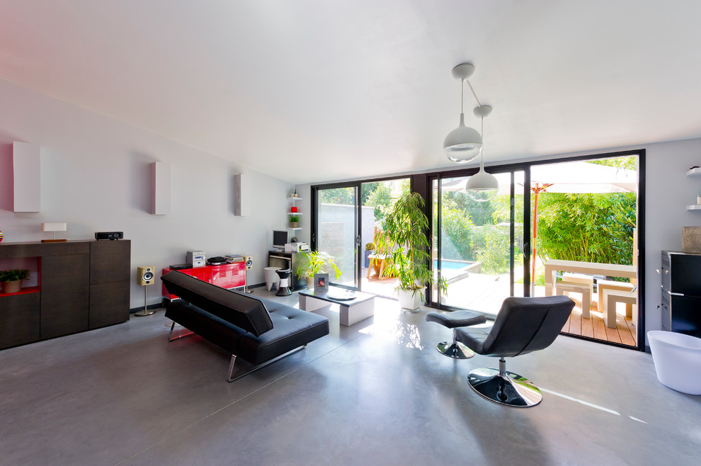 Стильный дизайн: открытая гостиная комната в современном стиле с серыми стенами и бетонным полом без камина, телевизора - последний тренд