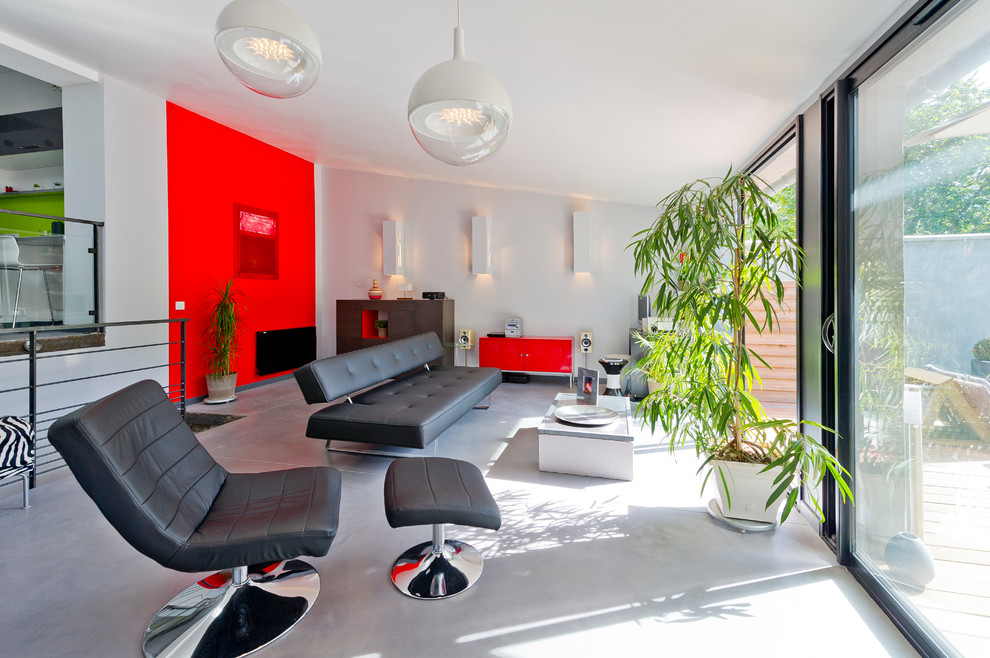Источник вдохновения для домашнего уюта: открытая гостиная комната в современном стиле с красными стенами, бетонным полом и акцентной стеной без камина, телевизора