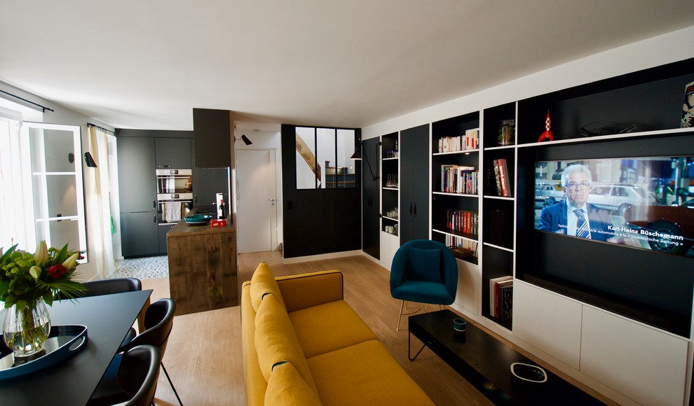 Idee per un soggiorno design di medie dimensioni e aperto con libreria, parquet chiaro e TV a parete