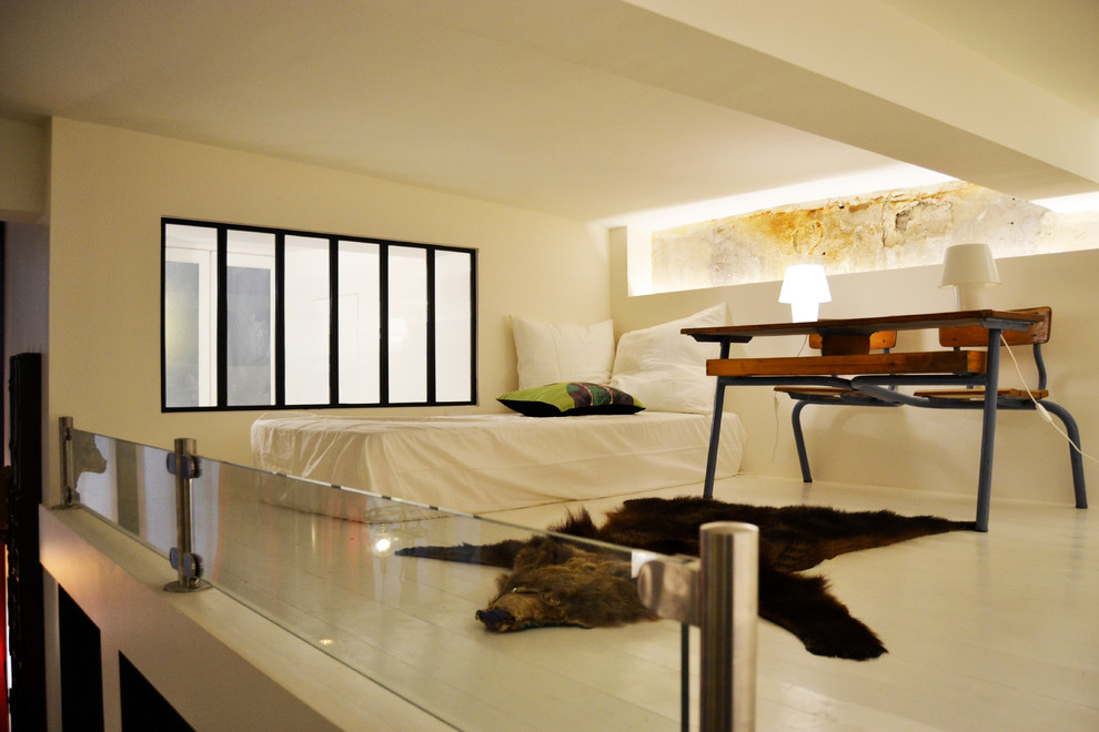 Immagine di un piccolo soggiorno minimal stile loft con libreria, pareti beige, pavimento in legno verniciato, nessun camino, nessuna TV e pavimento beige
