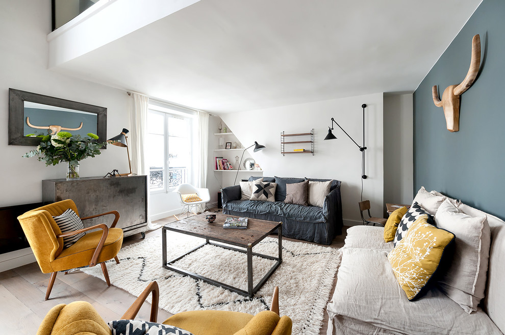 This is an example of a large industrial grey and yellow living room in Paris with a reading nook, blue walls, light hardwood flooring, no fireplace and no tv.