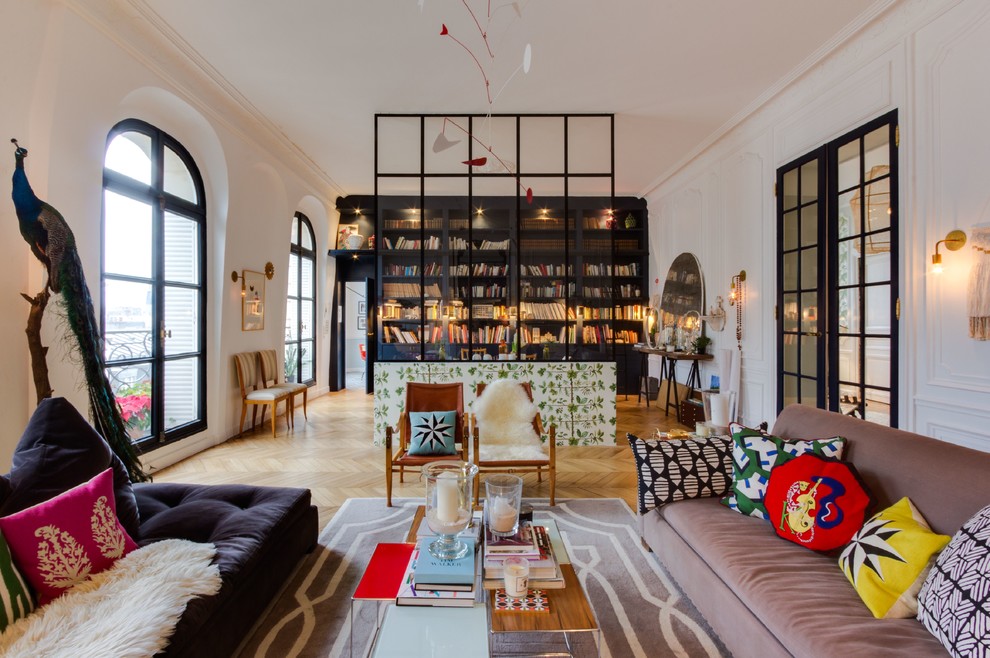 Diseño de biblioteca en casa abierta bohemia con paredes blancas, suelo de madera en tonos medios y suelo marrón