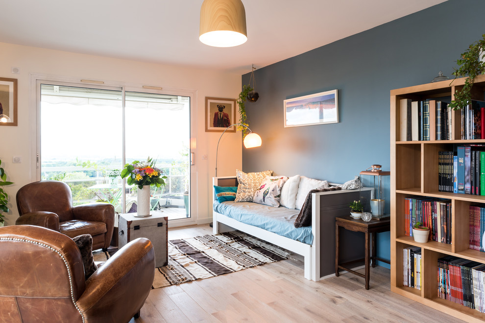 Diseño de salón abierto bohemio con paredes azules, suelo de madera clara y suelo beige