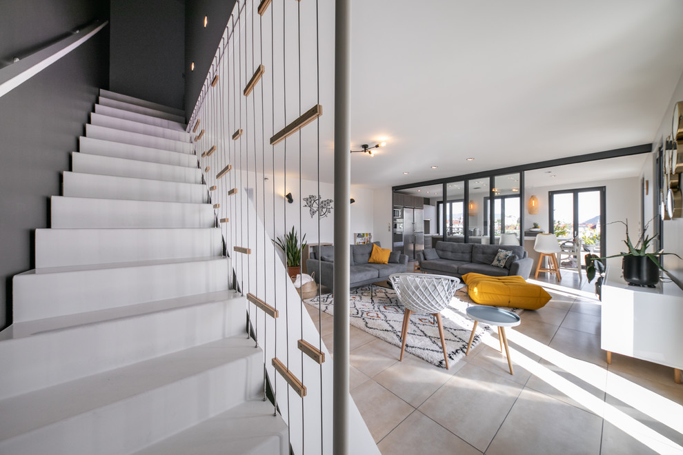 Cette image montre un grand salon design ouvert avec une salle de réception, un mur gris, un sol en carrelage de céramique et un sol beige.