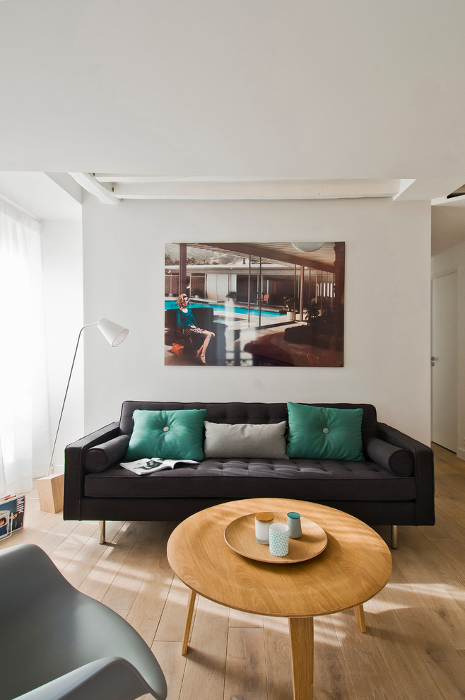 Example of a small danish open concept medium tone wood floor living room design in Paris with white walls